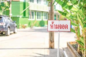Thailand Sign No Parking standy beside the road in vilage of Bangkok Thailand. The Thai text means No Parking. photo