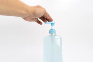 Asian mand hand holds a gel alcohol pump bottle and ready to pushes on it. It's an isolated object on the white clear screen in studio light. photo