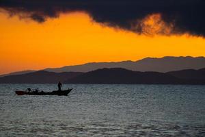 Thailand sea in twilight time with Silhouette ship and fisherman in the sea photo