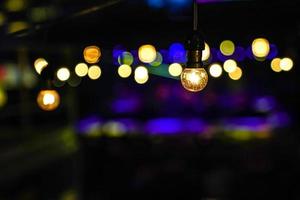 Focus on Vintage circle hanging lamp on the line with blur outdoor concert in the night bokeh background. photo