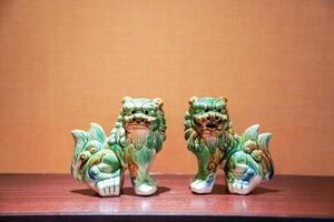 twin green seramic lion stand in the middle of frame with tungsten light. photo