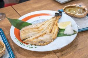 pescado cocido japonés en un plato sobre una mesa de madera en un restaurante japonés abierto las 24 horas. foto