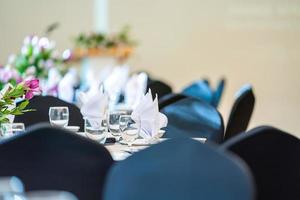 almuerzo o cena de lujo en el patrón de mesa larga con una mesa cubierta negra con decoración floral. foto