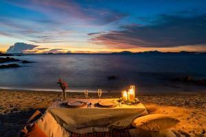 Romantic Dinner Table set beside the beach in the sunset twilight time, at Munnok Island, Thailand. photo