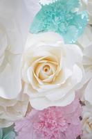 Pastel paper flower cream white pink green blue colour with hand craft art on the white wood plate background. photo