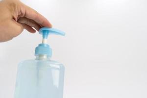 Asian mand hand holds a gel alcohol pump bottle and ready to pushes on it. It's an isolated object on the white clear screen in studio light. photo