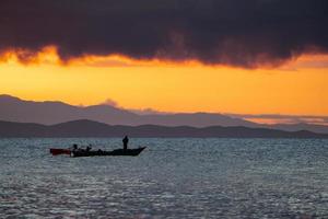 Thailand sea in twilight time with Silhouette ship and fisherman in the sea photo