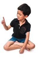 Isolated of sitting boy looking at his index finger photo