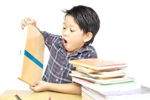 un chico asiático grita mientras mira un montón de libros aislados sobre fondo blanco foto