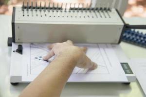 Man making report using comb binding machine - people working with stationary tools concept photo