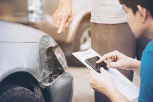 agente de seguros que trabaja durante el proceso de reclamación de accidentes de coche en el lugar - concepto de reclamación de seguros de personas y coches foto