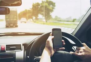 primer plano de un hombre conduciendo un coche peligrosamente mientras usa el teléfono móvil foto