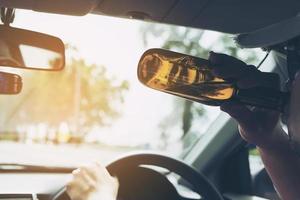 Man drinking beer while driving a car photo