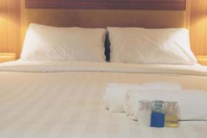 Hotel towel with shampoo and soap bottle set on white bed photo