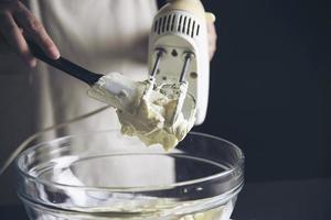 señora haciendo pastel poniendo crema con espátula - concepto de cocina de panadería casera foto