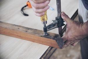 Carpenter doing wood work using clamping hand tool photo