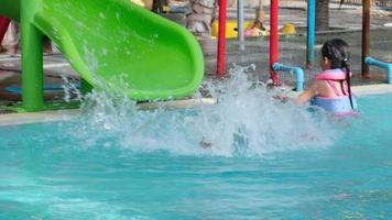 kind op waterglijbaan bij aquapark. klein meisje met plezier bij het zwembad. zomervakantie. video