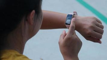 Close-up shot of a female runner counting calories burned on a smart watch. A young athlete uses a smartwatch to check results while practicing outdoors. video