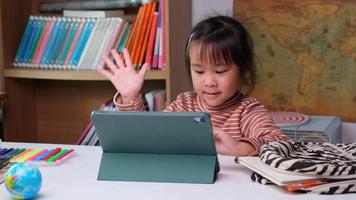 süßes kleines mädchen, das einen stift hält, der an einem tablet arbeitet. kind, das digitale tabletten verwendet, um informationen im internet für ihre hausaufgaben, hausunterricht, e-learning-online-bildung zu suchen.