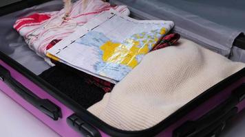 Female hands packing traveler case on bed. Preparation travel suitcase at home. Woman packing suitcase for summer travel. Traveling preparation concept.