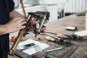 Carpenter using air nail gun doing wooden furniture work photo