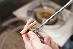 Man is installing soft gas pipe with T junction connector - technician working at home kitchen photo