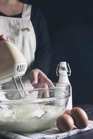 señora haciendo pastel poniendo crema con espátula - concepto de cocina de panadería casera foto