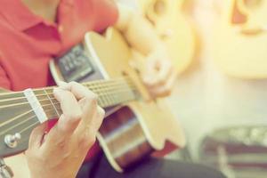 Vintage photo of man is playing guitar with hanging guitars background