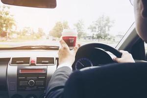 Man driving car while holding a cup of coffee photo