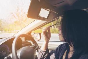 Woman makeup her face using eyebrow pencil while driving car, unsafe behavior photo