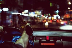 Man drink beer while driving at night in the city dangerously, left hand drive system photo