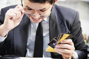 Businessman holding credit cards thinking seriously about payment loan problem - people with personal financial crisis concept photo