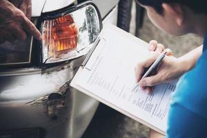 agente de seguros que trabaja durante el proceso de reclamación de accidentes de coche en el lugar - concepto de reclamación de seguros de personas y coches foto