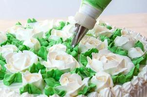 Making rose and leaves from cream for cake decoration photo