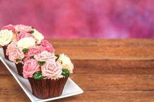 Roses cupcake on wooden floor with multicolor background photo