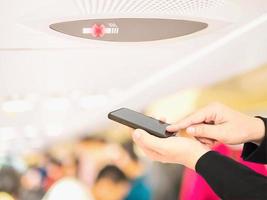 Businessman is using - touching mobile phone over blurred passengers in an commercial airplane photo