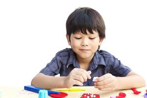 Asian lovely boy is playing clay happily over white background photo