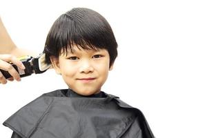 un niño se corta el pelo con un peluquero aislado sobre fondo blanco foto