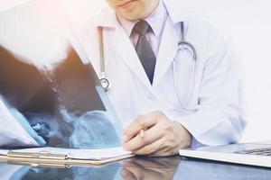 Doctor examine x-ray film over white background photo