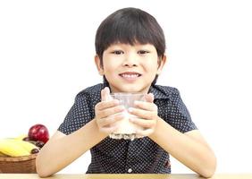 Asian boy is drinking a glass of milk over white background photo