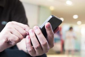 A man is using telephone over colorful blurred bokeh light in office and people background photo
