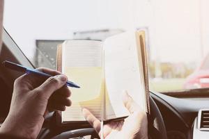 Man writing notebook while driving car, dangerous behavior photo