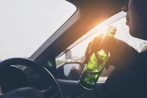 Man drinking beer while driving a car photo