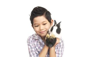 Asian kid playing with lovely baby rabbit isolated over white photo