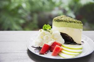 Colorful green tea favor cake with well decorated fruit pieces and whipped cream in white plate - cake recipe menu concept photo