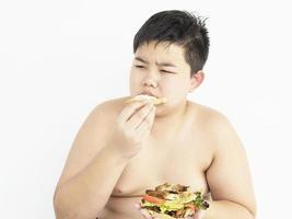 un chico gordo está felizmente comiendo un sándwich. foto