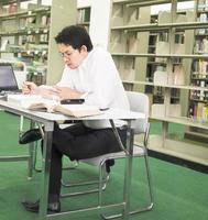 Sitting man is reading and working in a library background photo