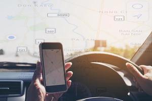 la mujer está conduciendo un camión peligrosamente mientras sostiene y mira un navegador de mapas en su teléfono móvil con un mapa de ruta superpuesto foto