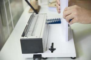 Man making report using comb binding machine - people working with stationary tools concept photo