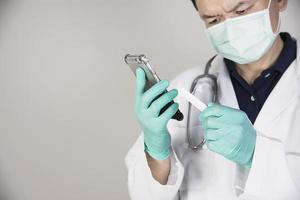 Asian doctor seriously using telephone while checking covid-19 virus antigen test kit result photo